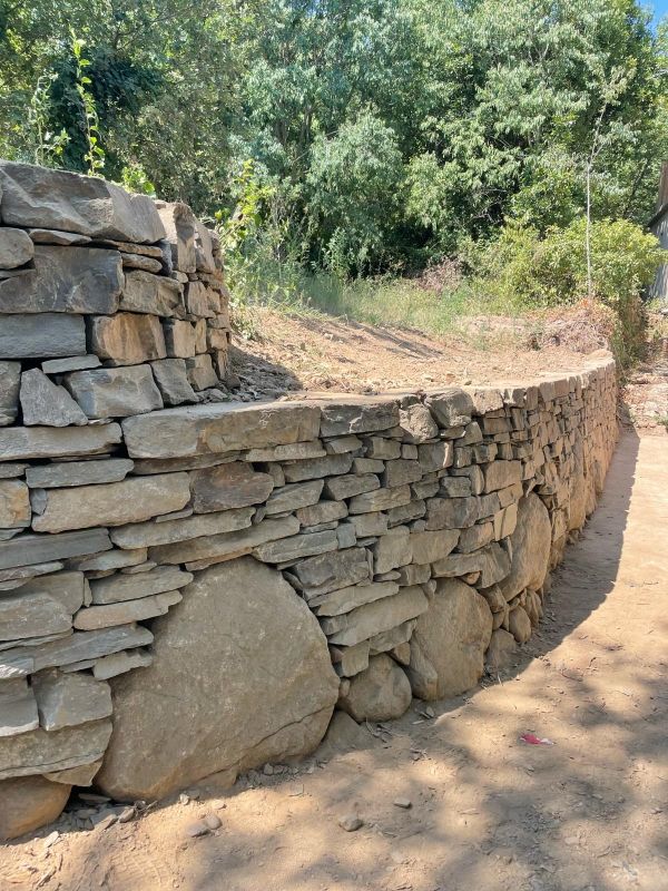 Mur en pierre courbé avec des rochers à l'intérieur